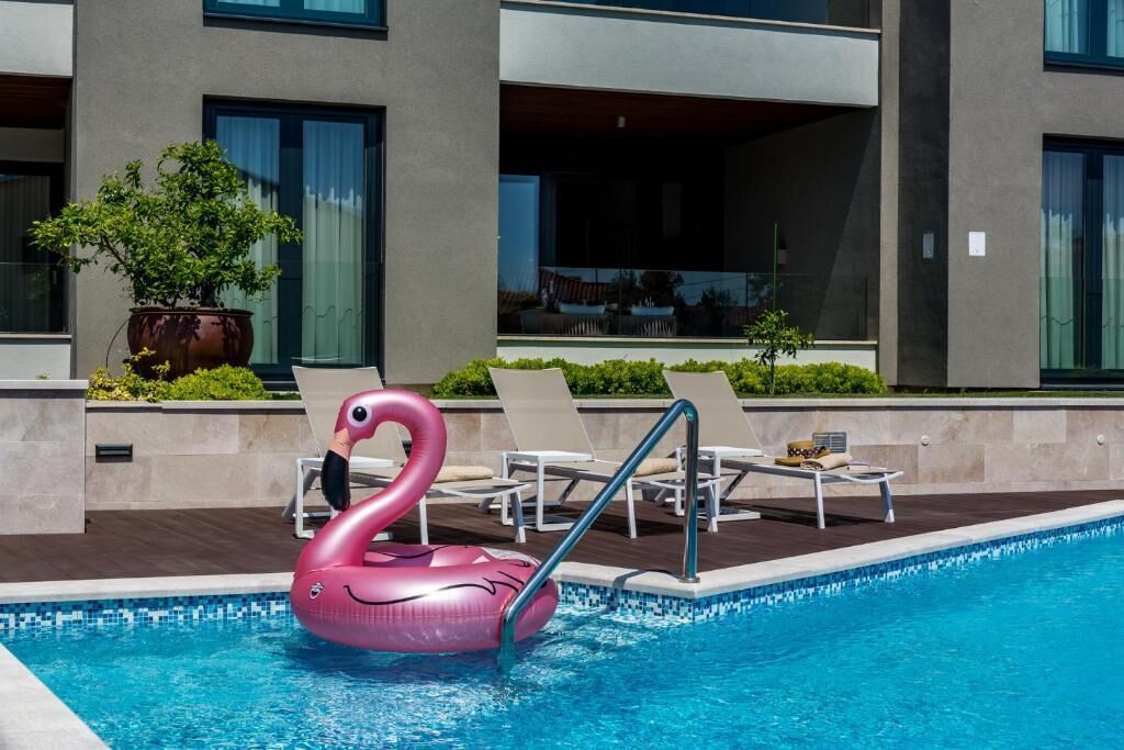 Ein Swimmingpool mit einem rosa Schwaneinhorn-Badeartikel, Liegestühlen und einem Blumentopf.