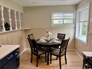 A dining area with a round table, four chairs, and a vase of flowers.