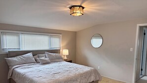 Une chambre à coucher avec un grand lit, une lampe de chevet, un miroir rond et un luminaire au plafond.