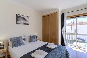 Ein Hotelzimmer mit Bett, Nachttisch, Nachttischlampe, einem Fenster mit Blick und einer Tür.