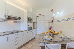 Eine moderne Küche mit weißen Schränken, einer Mikrowelle, einem Backofen und einem Essbereich mit einem für das Frühstück gedecktem Tisch.