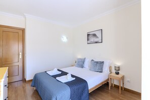 A bedroom with a bed, pillows, a bedside table with a lamp, a door, and a wall-mounted picture. - #338 Peaceful Family House | Outdoor Space (Albufeira)