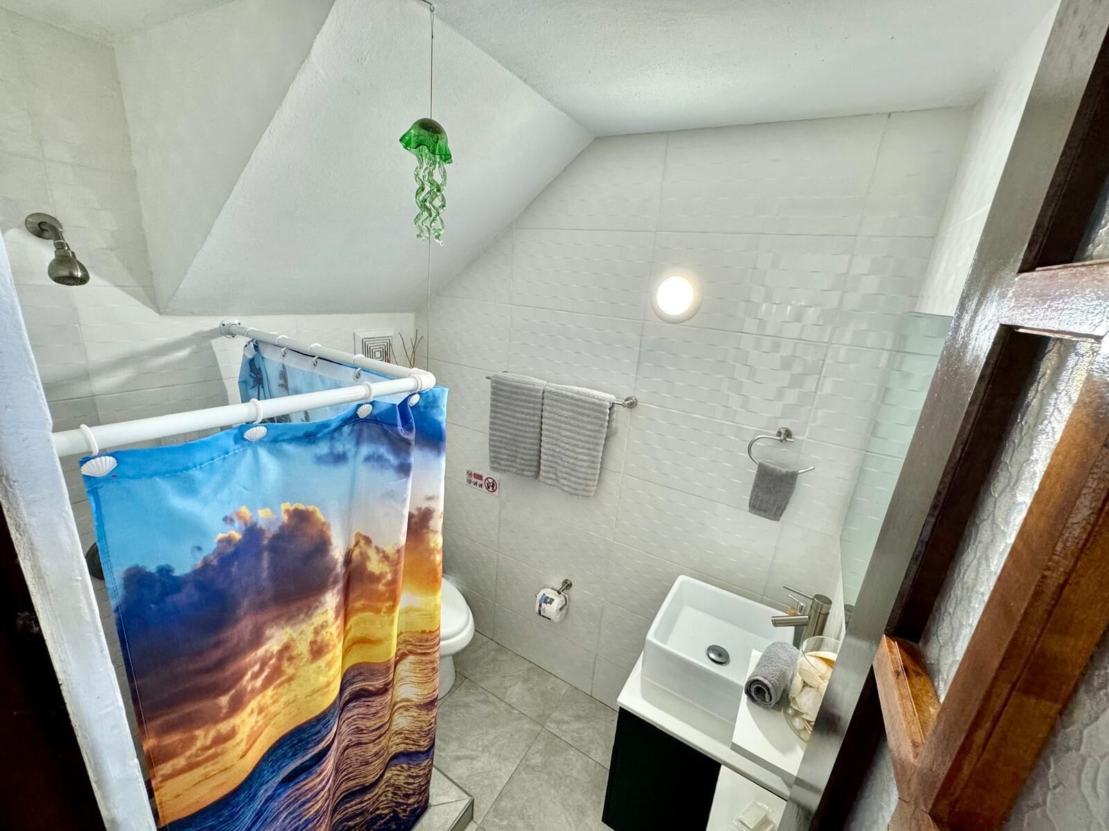 Ein Badezimmer mit Duschvorhang, Toilette, Waschbecken und Handtuchhalter.
