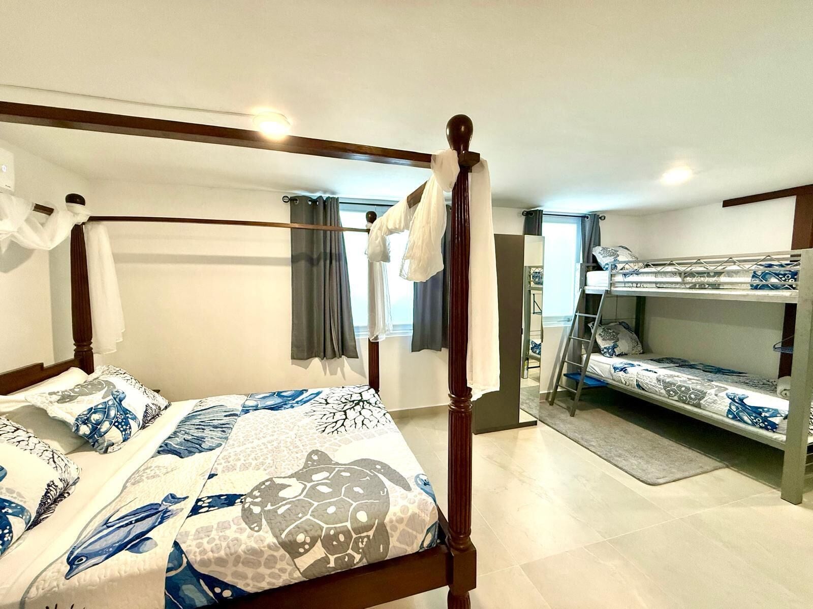 Un dormitorio con cama con dosel, una litera y una ventana con cortinas.