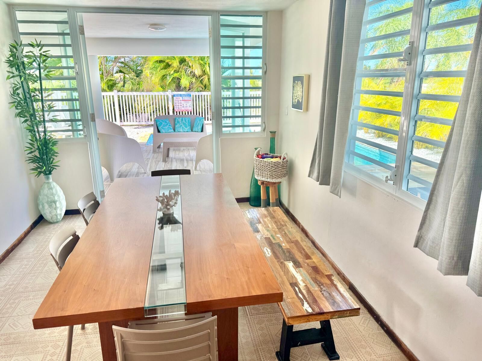Un comedor con mesa de madera, sillas, una mesa central de vidrio y vistas al exterior.