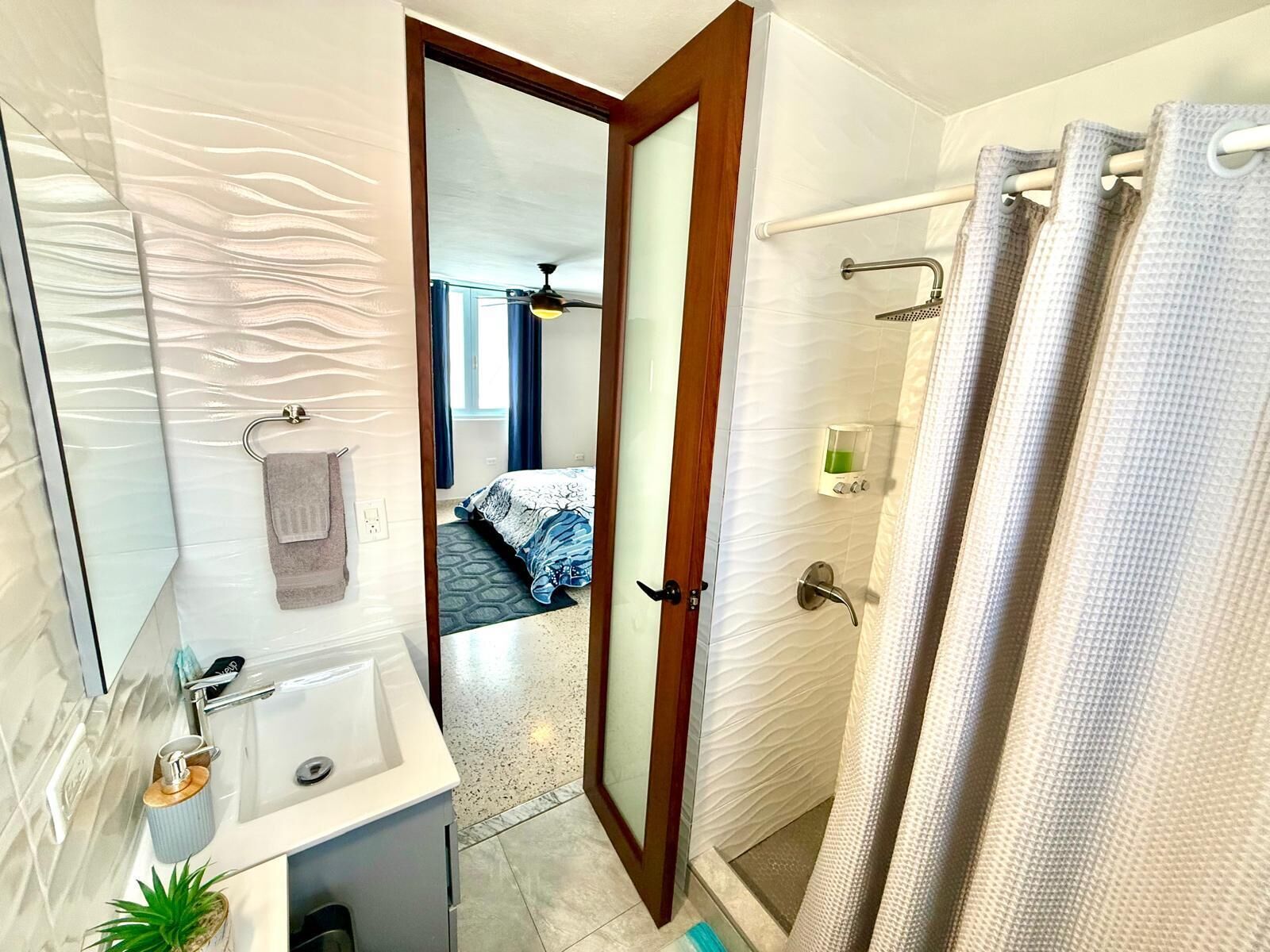 Un baño con ducha, lavabo y espejo.