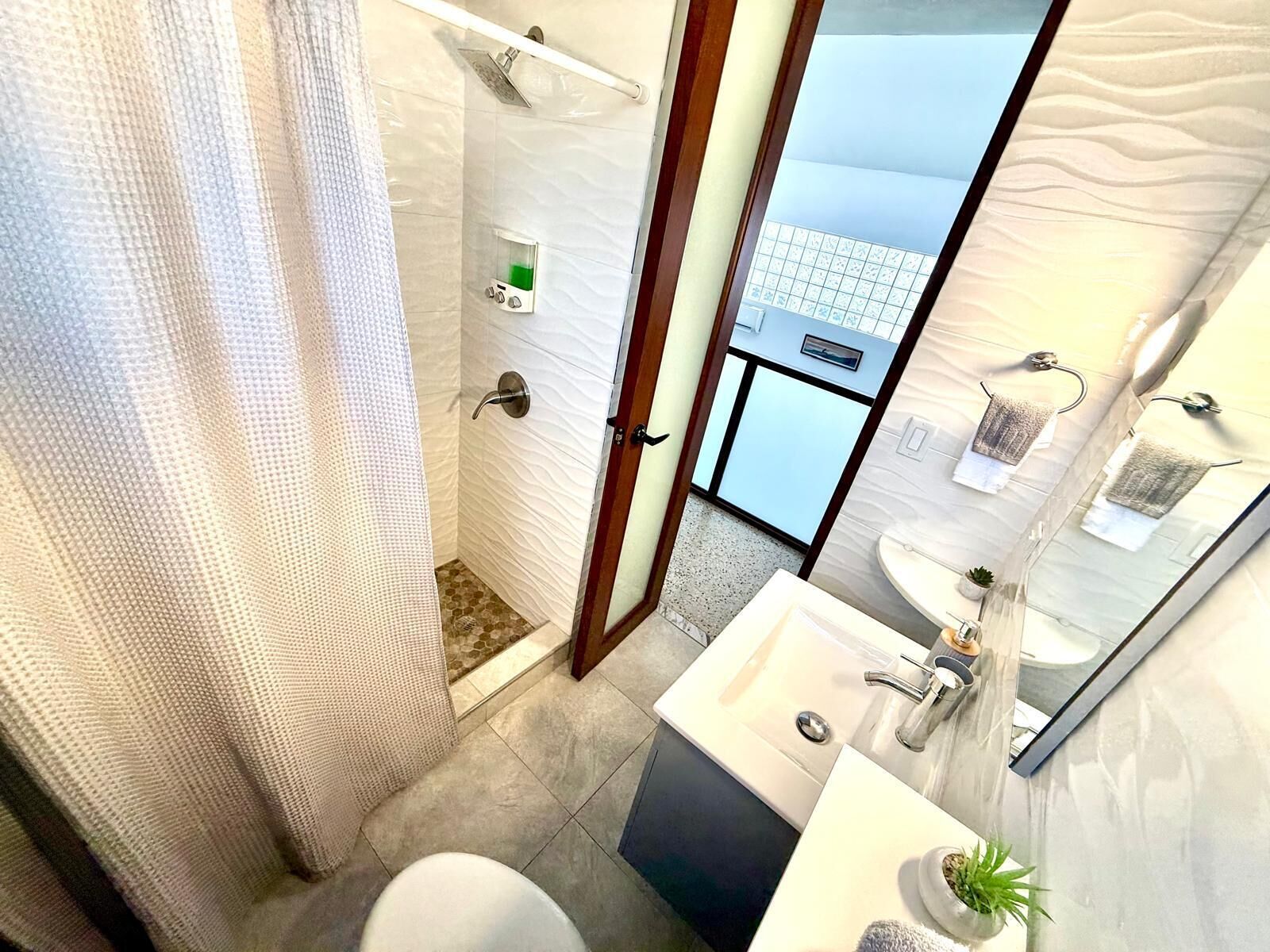 A modern bathroom with a shower, toilet, and sink.