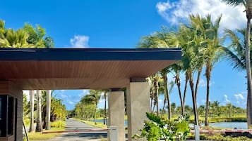 A covered walkway with palm trees and a clear sky.