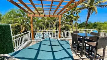 A covered outdoor area with a pool, seating, and a view of palm trees.