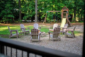 Eine Terrasse mit Adirondack-Stühlen und einer Steinkaminfeuerstelle.
