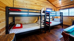 A room with bunk beds, wooden walls, and a window. - Over Yonder Inn | Hot Tub, Firepit & Pool Table (Broken Bow)