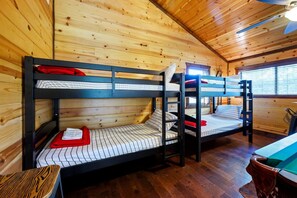 Ein Zimmer mit Etagenbetten, Holzwänden und einem Fenster.