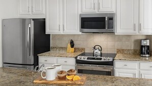 A kitchen with white cabinets, a stainless steel refrigerator, a microwave, an oven, and a coffee maker. - 2 Bedroom Villa Harbour Club Resort w/ Amenities (Hilton Head Island)