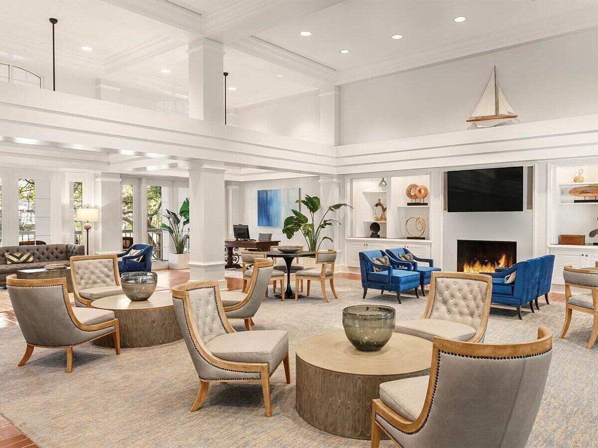 A spacious hotel lobby with multiple seating areas, a fireplace, and a large TV screen.