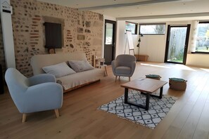 A modern living room with a sofa, two armchairs, a coffee table, and a patterned rug.