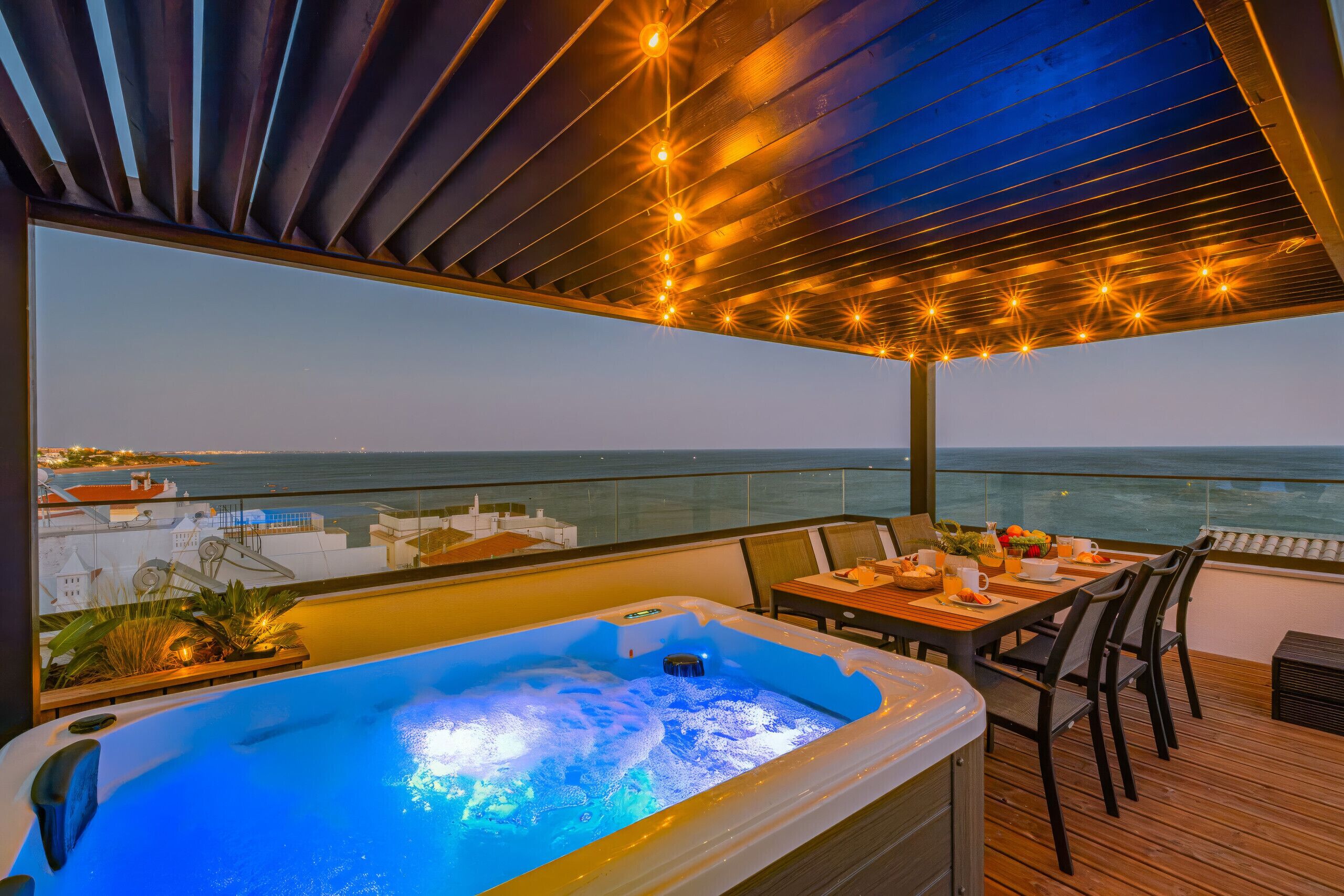 Een bubbelbad op een balkon met uitzicht op zee en de skyline.