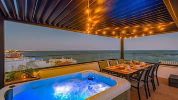 Een bubbelbad op een balkon met uitzicht op zee en de skyline.