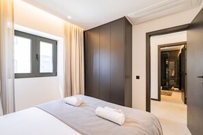 A modern hotel room with a bed, a window, and a door leading to a bathroom. - House with Rooftop & Jacuzzi in Albufeira (Albufeira)