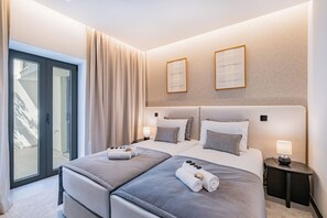 A modern hotel room with a large bed, two bedside tables, and a sliding glass door leading to a balcony. - House with Rooftop & Jacuzzi in Albufeira (Albufeira)