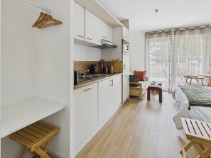 Un ambiente compatto con angolo cottura, un letto, un'area salotto e un tavolo da pranzo.