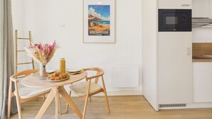 Een moderne keuken met witte kasten, een magnetron en een lijst met een strandgezicht.