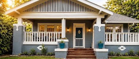 A two-story house with a front porch, a stone pathway, and a well-maintained lawn.
