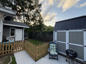 A backyard with a wooden fence, a grill, and a chair. - Anchored in Paradise, Walk to Beach & Island View Casino (Gulfport)