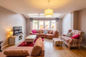 A living room with a sofa set, a television, a coffee table, and a red rug. - Pet-Friendly 3-Bed Home · Sleeps 6 · Free Parking in Salford (Greater Manchester)
