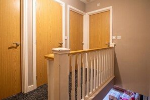 A staircase with a white railing, wooden doors, and a carpeted floor. - Pet-Friendly 3-Bed Home · Sleeps 6 · Free Parking in Salford (Greater Manchester)