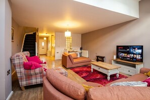 Ein Wohnzimmer mit einer Couch, einem Couchtisch, einem Fernseher und einer Treppe, die in einen anderen Raum führt.