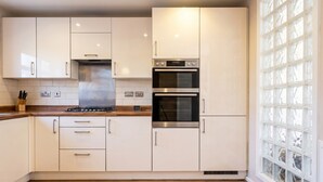 Une cuisine avec des meubles blancs, une cuisinière en acier inoxydable et un four encastré.