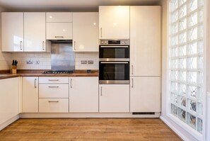 A kitchen with white cabinets, a stainless steel range, and a built-in oven. - Pet-Friendly 3-Bed Home · Sleeps 6 · Free Parking in Salford (Greater Manchester)