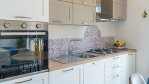 Una cocina con estufa, horno, pileta y alacenas.