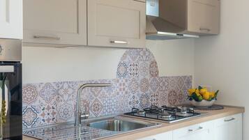A modern kitchen with a gas stove, stainless steel sink, and patterned backsplash.