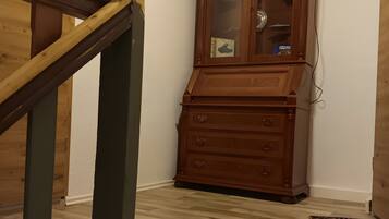 A wooden staircase with a handrail, a wooden cabinet with glass doors, and a patterned rug on the floor.