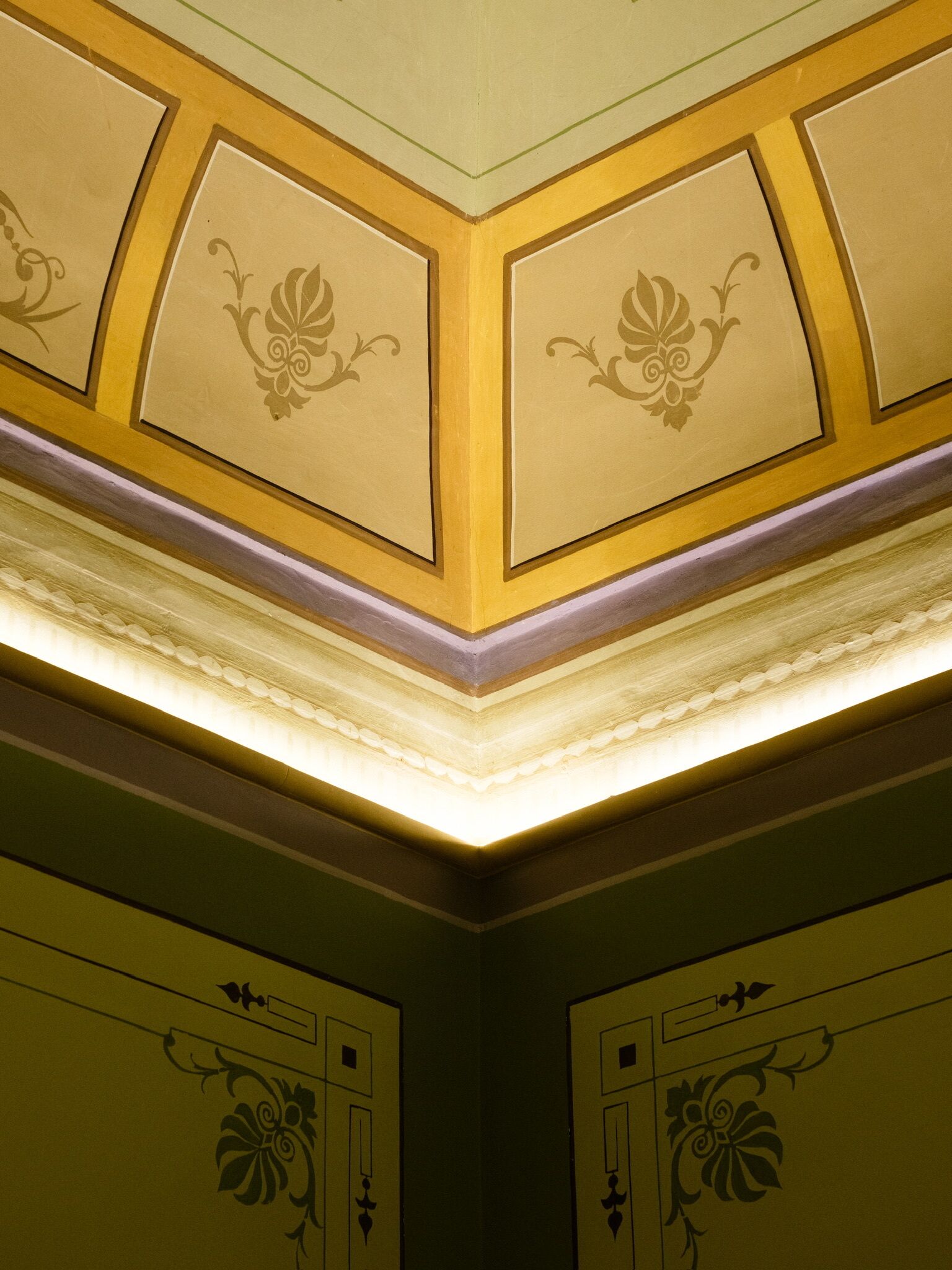 A room with a decorative ceiling featuring geometric patterns and recessed lighting.