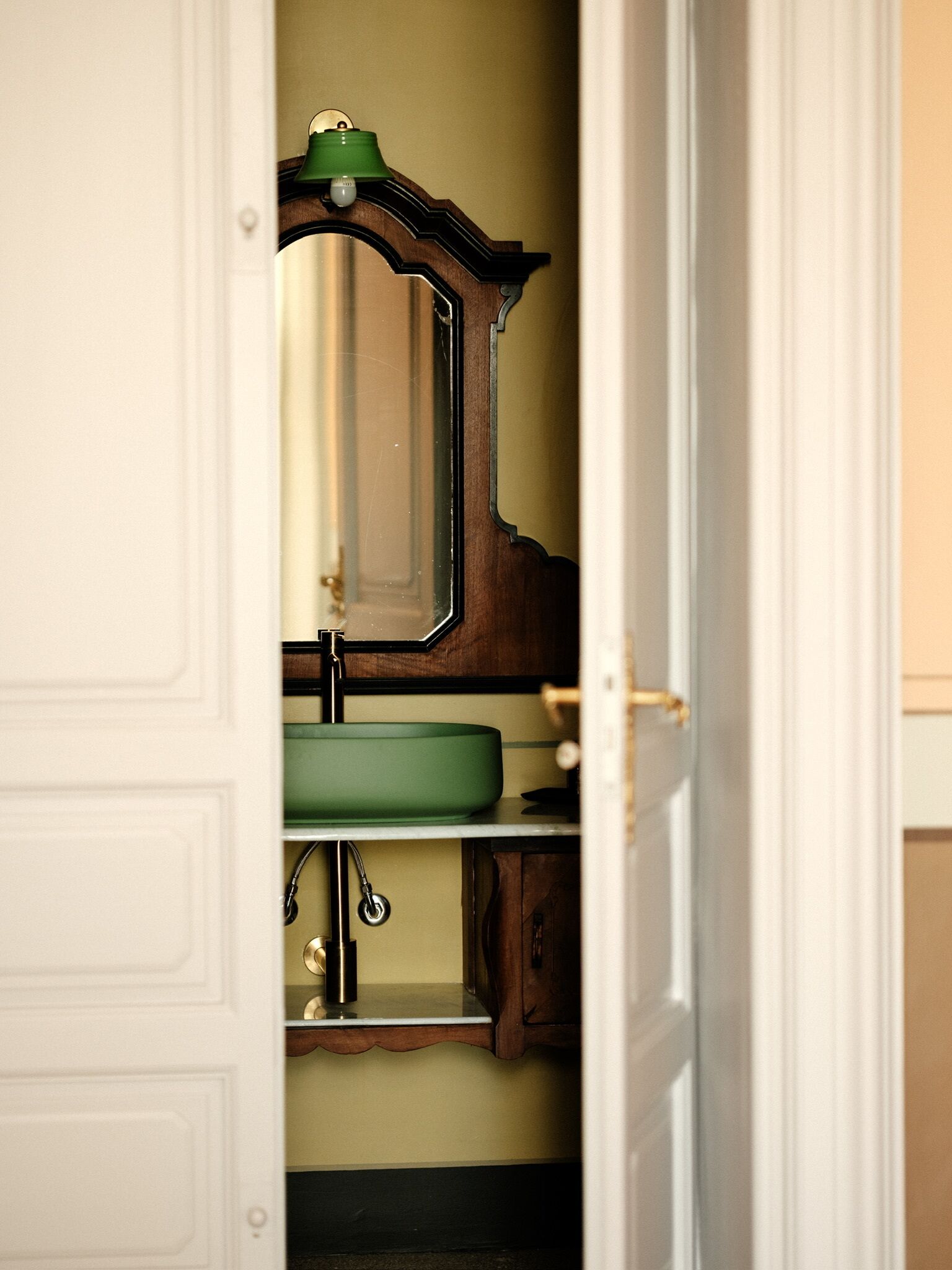 A bathroom with a wooden vanity, a green sink, and a mirror.