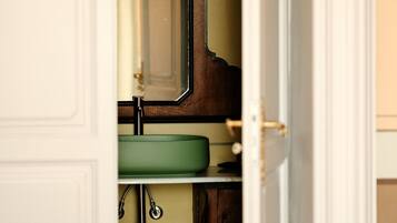 A bathroom with a wooden vanity, a green sink, and a mirror.