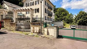Un edifici amb una entrada tancada per una reixa, un rètol que diu 'LA PERGOLA' i un senyal de pàrquing que indica una zona d'aparcament.