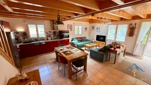 A cozy interior with a kitchen, dining area, and living room, featuring wooden beams, a TV, and a sofa. - La Pergola Le Mont Dore (6 people) (Mont-Dore)