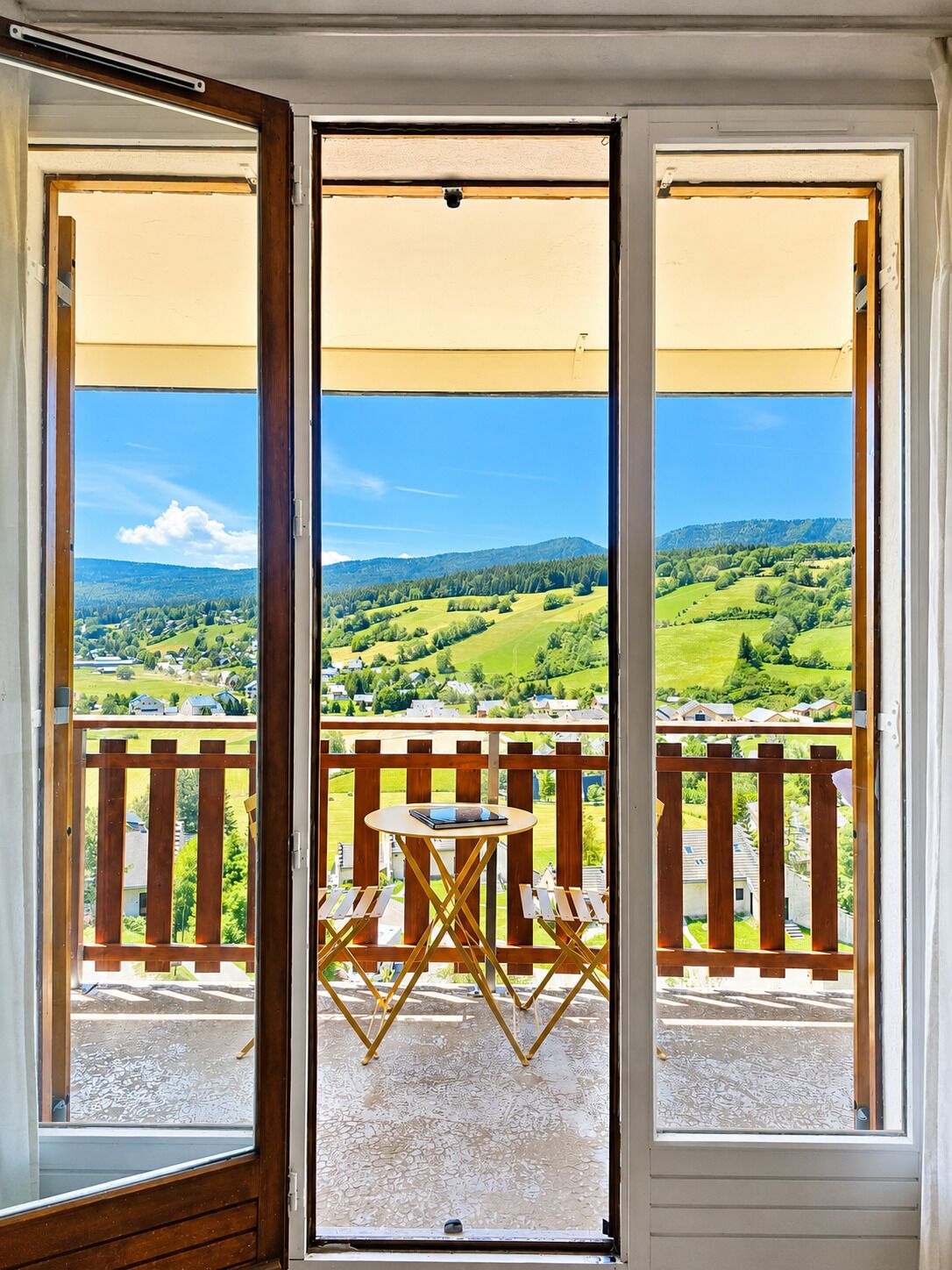 Un balcón con mesa y sillas, con vistas a un paisaje verde.
