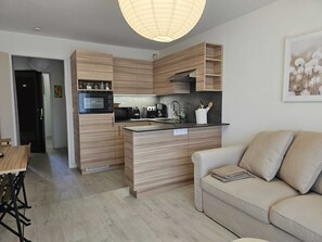A modern kitchen with wooden cabinetry, a built-in microwave, and a coffee maker.