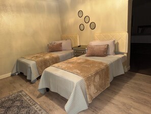 A hotel room with two beds, a nightstand, a dresser, and a decorative wall with circular mirrors.