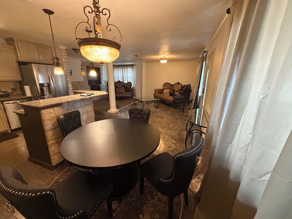 A modern kitchen with granite countertops, a central island, and a dining area with a round table and four chairs.