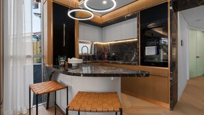 A modern kitchen with a curved island, bar stools, and a built-in oven. - The Sandstone, Neutral Bay (Neutral Bay)