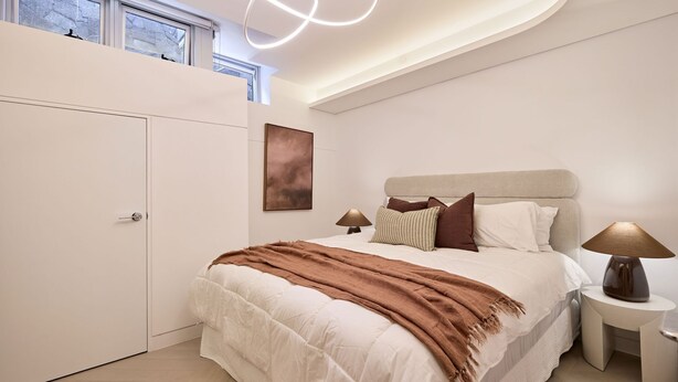 A bedroom with a bed, bedside tables, a painting, and a wardrobe. - The Sandstone, Neutral Bay (Neutral Bay)
