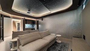 Ein modernes Interieur mit gewölbter Decke, einer Couch, einem kleinen runden Tisch und einem Aquarium.