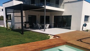 Une maison moderne dotée d’une piscine, d’une terrasse en bois et d’un espace salon extérieur.