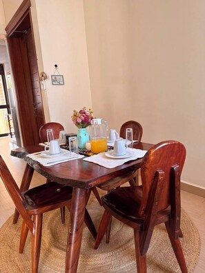 A dining table with chairs, a vase with flowers, and a pitcher of orange juice. - Lovely 3-bedroom apartment in peaceful Kampala neighborhood (Kampala)