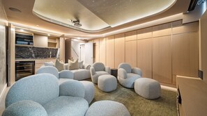 A modern interior with a seating area featuring round, textured ottomans, a built-in entertainment system, and a wooden wardrobe. - The Elara, Neutral Bay Isyd (Neutral Bay)